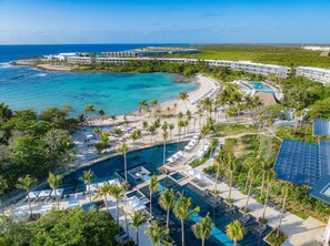 Un resort con varias piscinas, una playa y vista al océano.