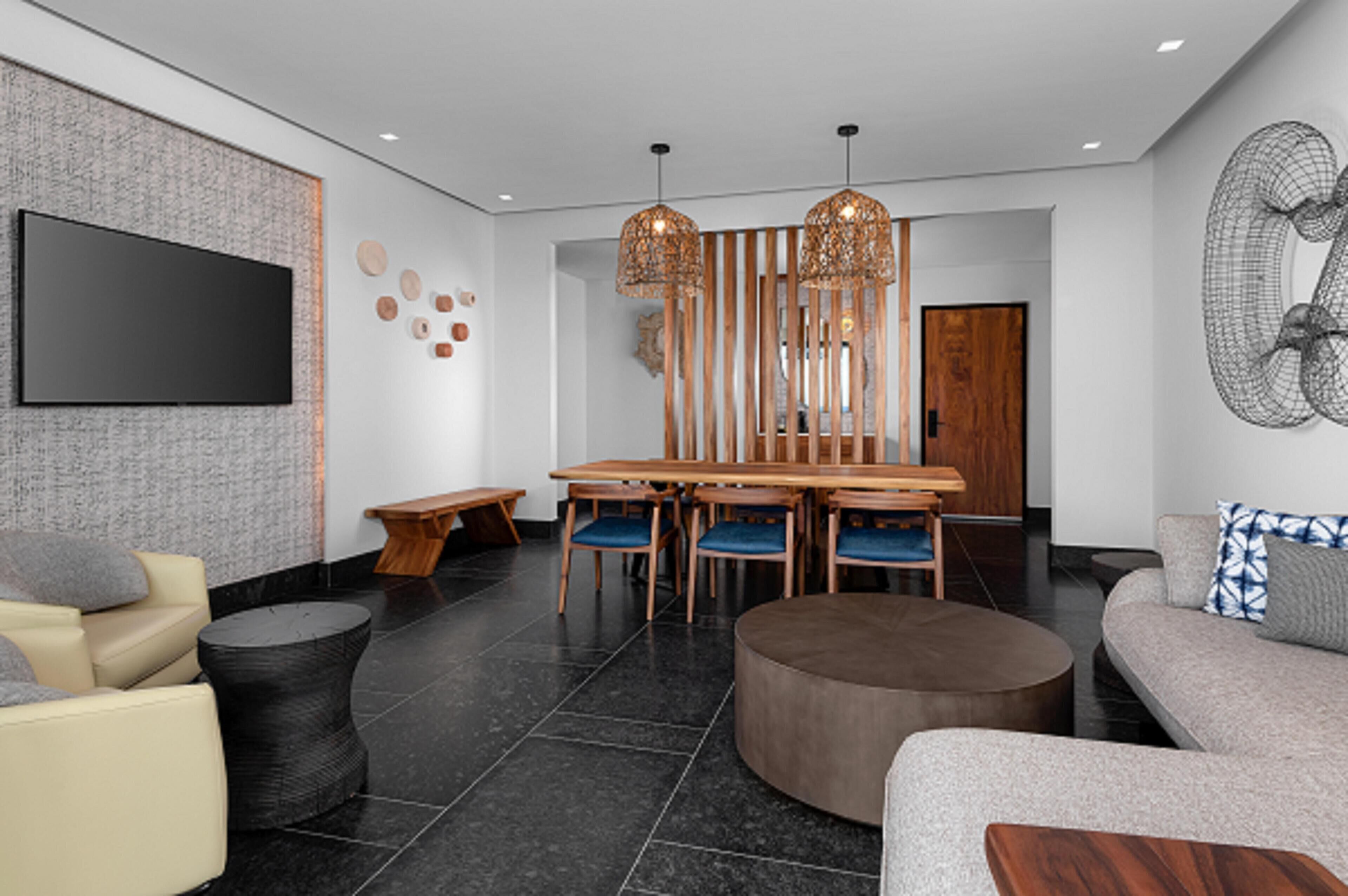 Un intérieur moderne comprenant un coin repas, des canapés et un téléviseur à écran plat.