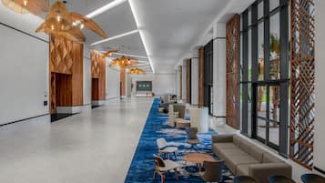 A spacious lobby with modern furniture, large windows, and decorative lighting.