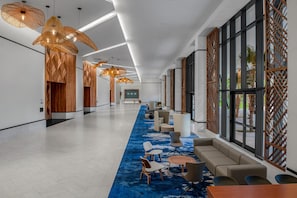 A spacious lobby with modern furniture, large windows, and decorative lighting.