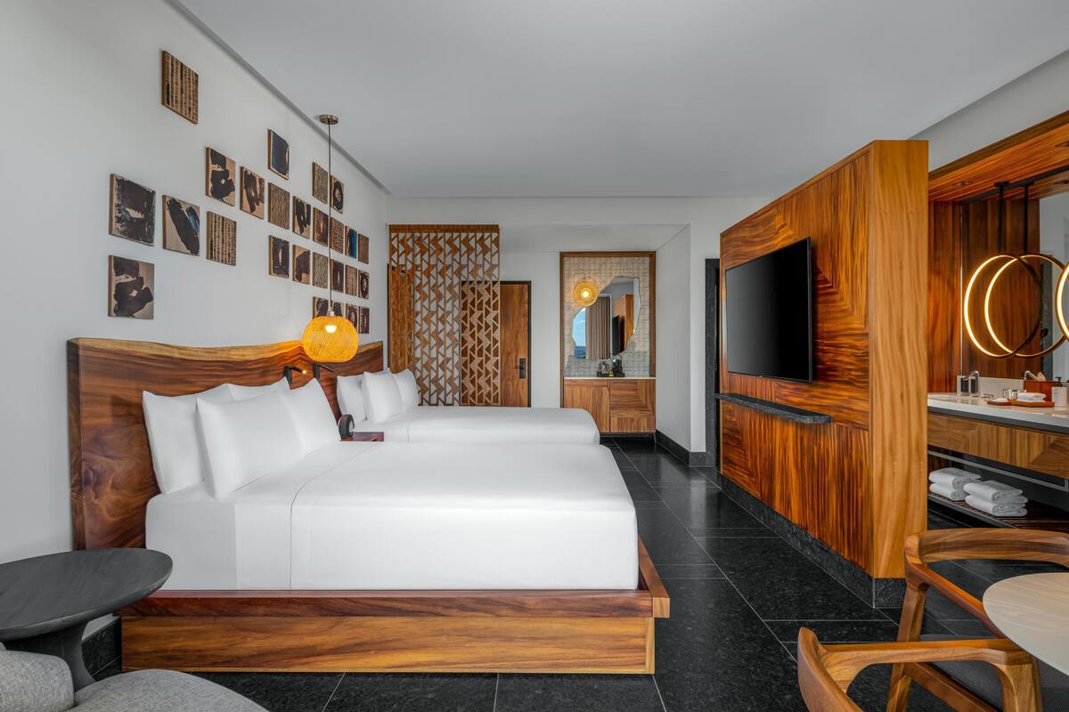 Une chambre d’hôtel moderne avec un grand lit, une télévision, une armoire en bois et un coin repas.