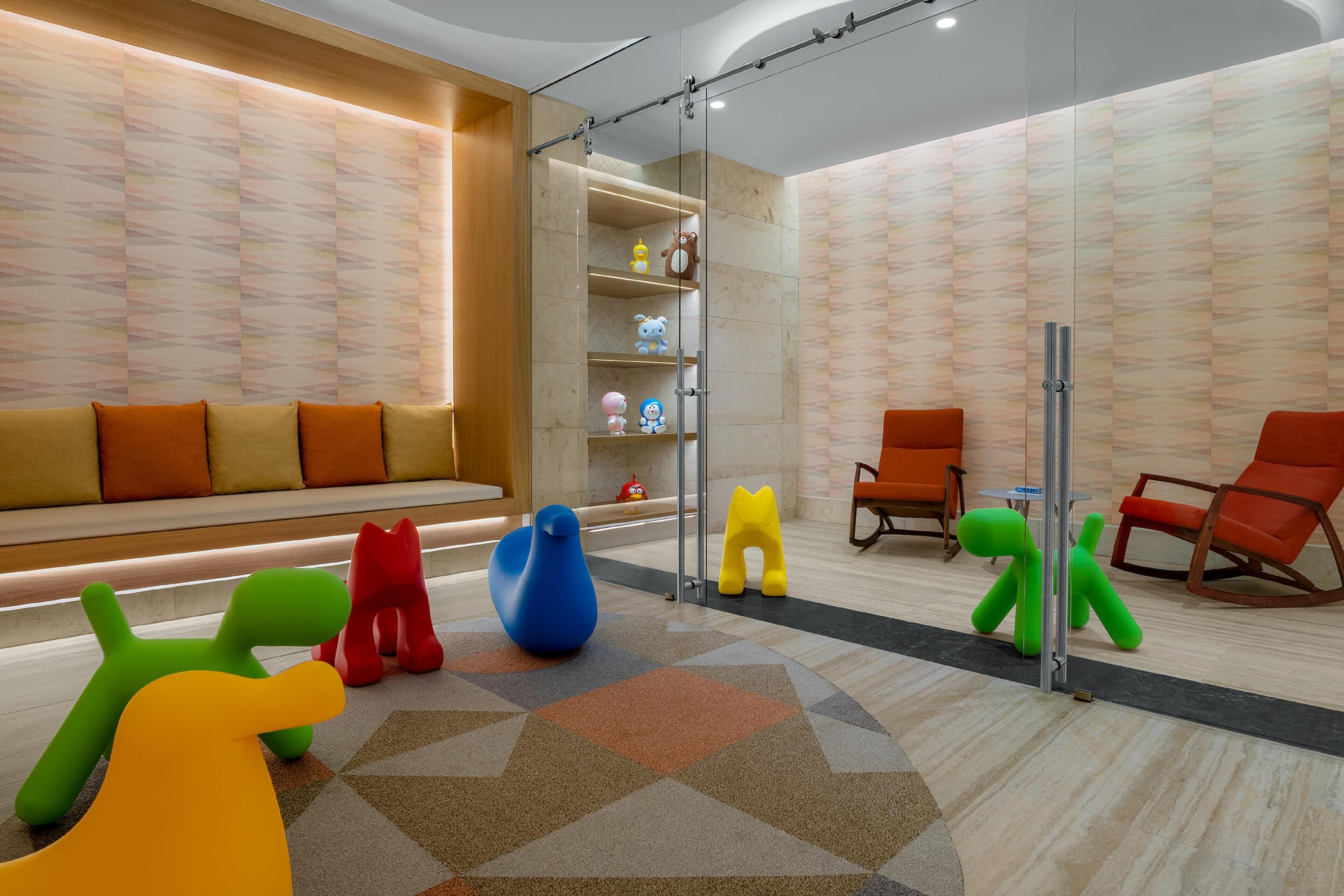 Een modern interieur met een zithoek, kleurrijke abstracte sculpturen en een behang met patroon.
