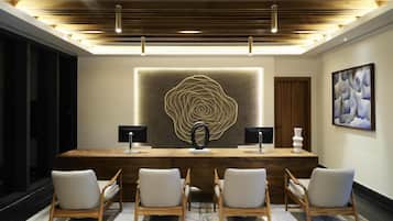 A modern conference room with a wooden desk, two monitors, and four chairs.