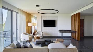 Un salon moderne comprenant un canapé, des fauteuils, une table basse, une cheminée et un téléviseur à écran plat fixé au mur.