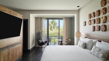 Hotelkamer met een groot bed, een televisie, een balkon met een tafel en stoelen, en een wand met houten kunstwerken.