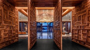 Un hall amplio con paneles de madera, un suelo reflectante y vistas a una zona de piscina.