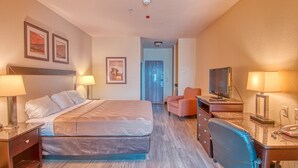 A hotel room with a bed, desk, chair, TV, and two lamps. - Express Inn & Suites (Norman)