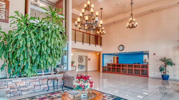 A spacious lobby with a checkered floor, a reception desk, and a staircase leading to an upper level. - Express Inn & Suites (Norman)