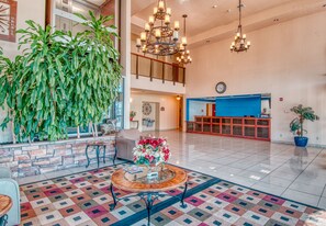 A spacious lobby with a checkered floor, a reception desk, and a staircase leading to an upper level. - Express Inn & Suites (Norman)