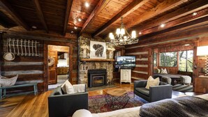 A rustic cabin interior with a fireplace, wooden walls, and a cozy seating area.