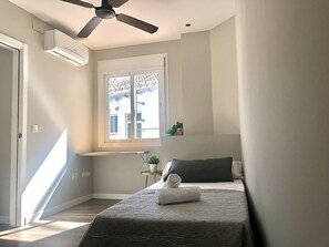 Ein Schlafzimmer mit Bett, Deckenventilator, Fenster mit Ausblick und Klimaanlage.