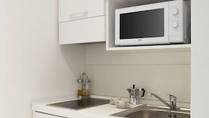 Een moderne keuken met witte kasten, een magnetron, een spoelbak en een koffiezetapparaat.