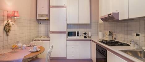A compact kitchen with white cabinets, a microwave, a stove, and a sink.