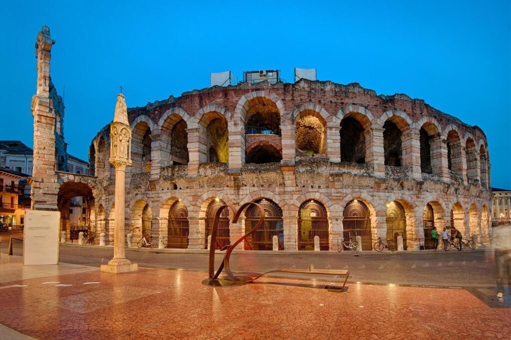 An ancient amphitheater with multiple arches and a central column.