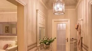 A hallway with a chandelier, a white door, a white sofa, and a decorative vase. - Αn enchanting residence in front of the Juliet house (Verona)