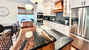 Eine moderne Küche mit Kochinsel, Edelstahlgeräten und einem Essbereich mit Holztisch und Stühlen.