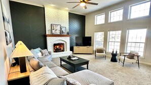 Una sala de estar moderna con chimenea, un sofá, una mesa de centro y un televisor.