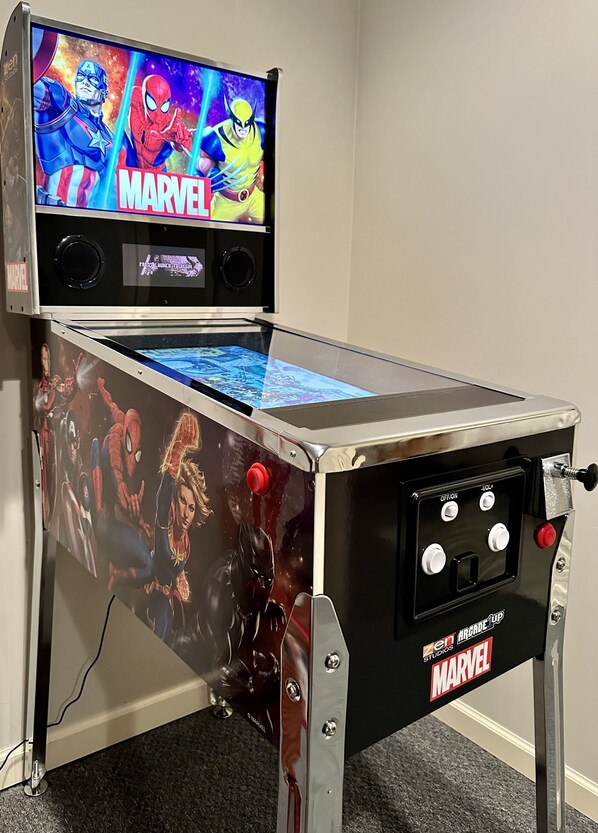 A table with a Marvel-themed arcade game featuring characters like Spider-Man and Wolverine.