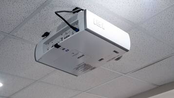 A ceiling-mounted projector with a control panel and a cable.