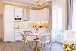 Une cuisine moderne avec des meubles blancs, un îlot central et un coin repas comprenant une table ronde et des chaises.