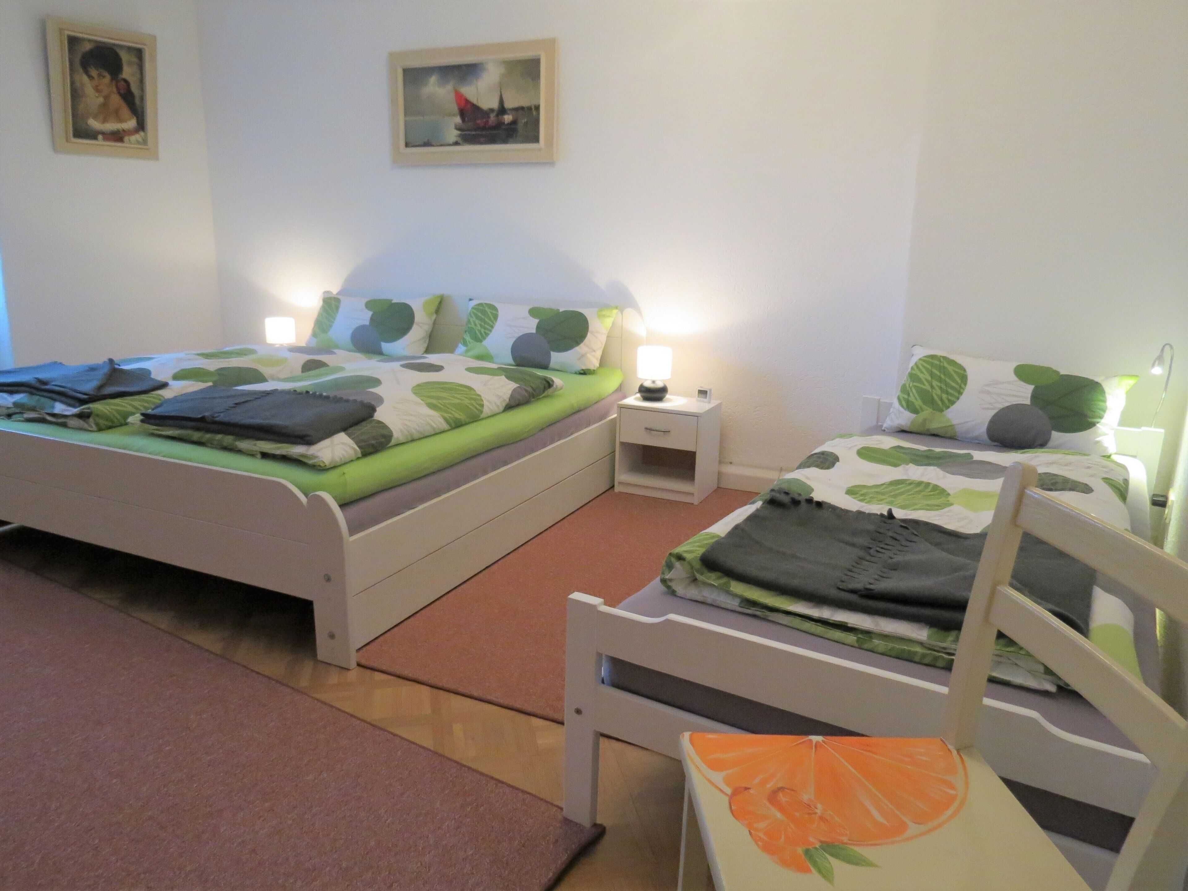 A bedroom with two single beds, a nightstand, a chair, and a painting on the wall.