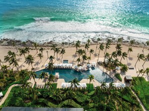 Na praia, areia branca, espreguiçadeiras, guarda-sóis 