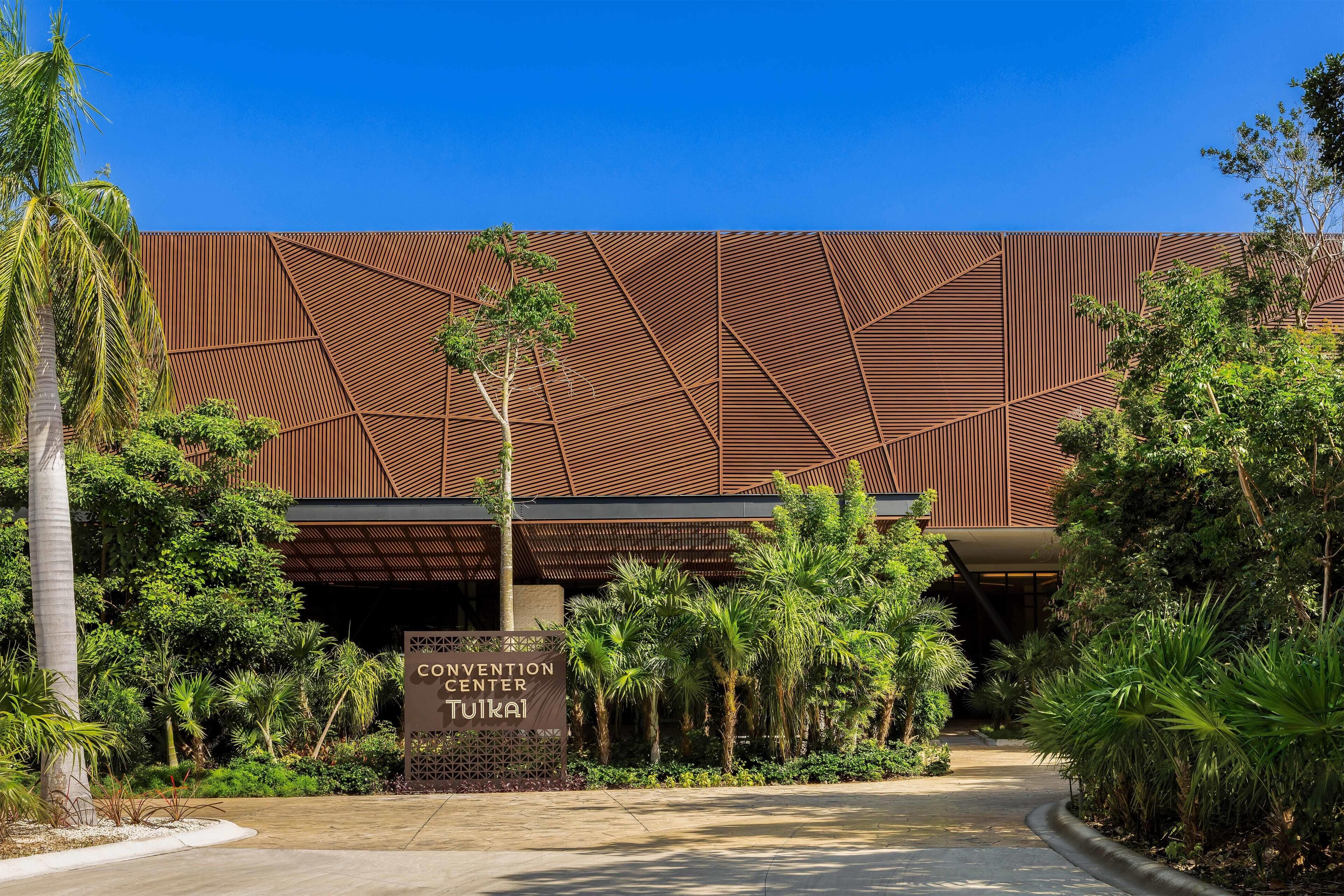 A modern building with a geometric facade and a sign reading "Convention Center Tuili".