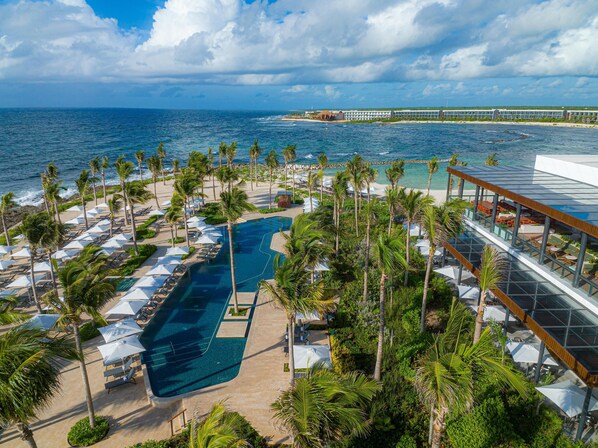 A resort with a swimming pool, palm trees, and a view of the ocean. - Hilton Tulum Riviera Maya All-Inclusive Resort (Tulum)