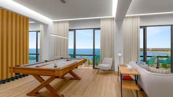 Una sala de estar moderna con una mesa de billar, un sofá y vistas al océano.