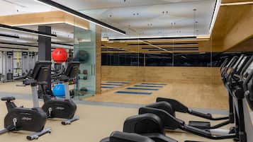 A modern gym with cardio equipment, weight machines, and a mirrored wall.