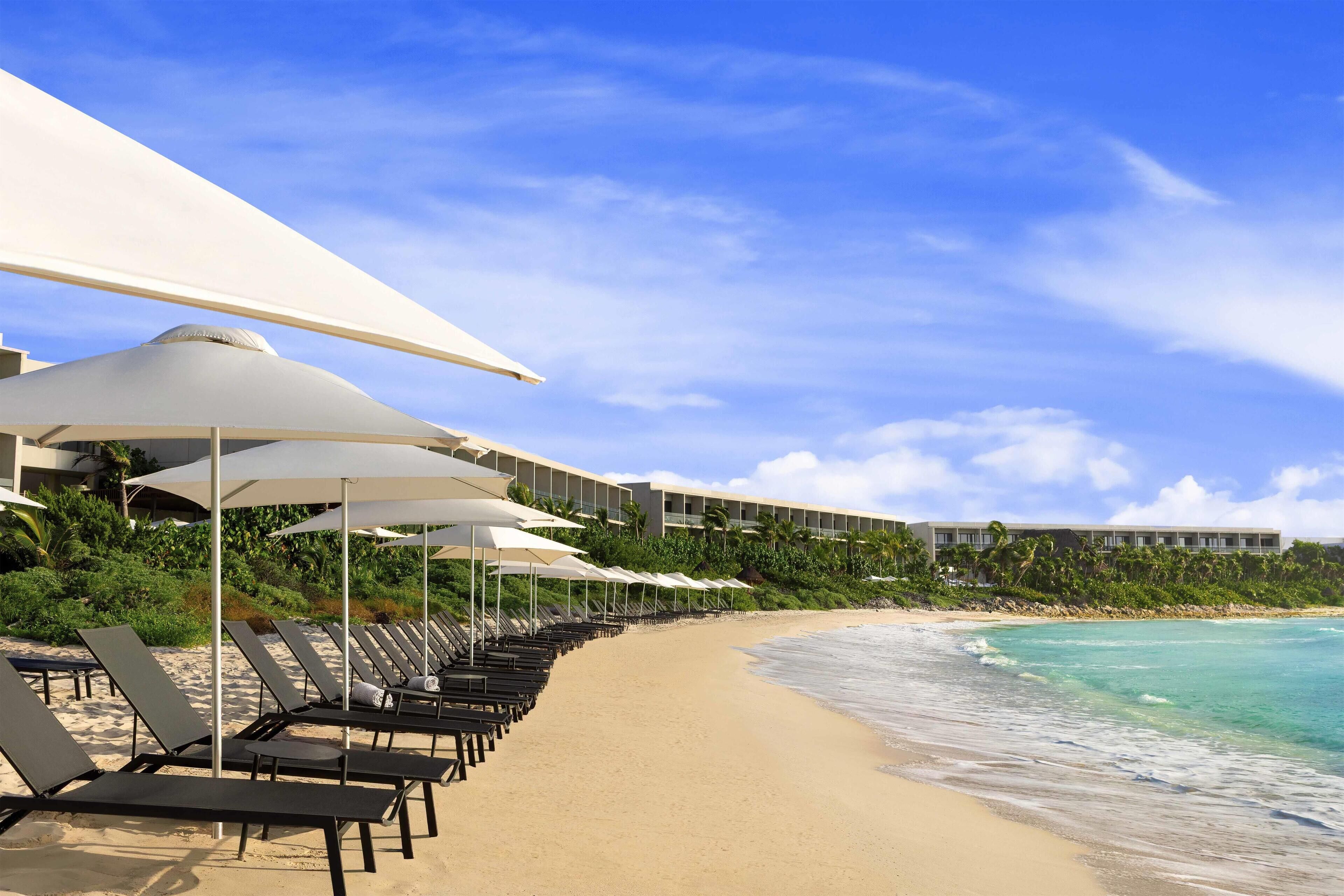 Aan het strand, wit zand, ligstoelen aan het strand, parasols