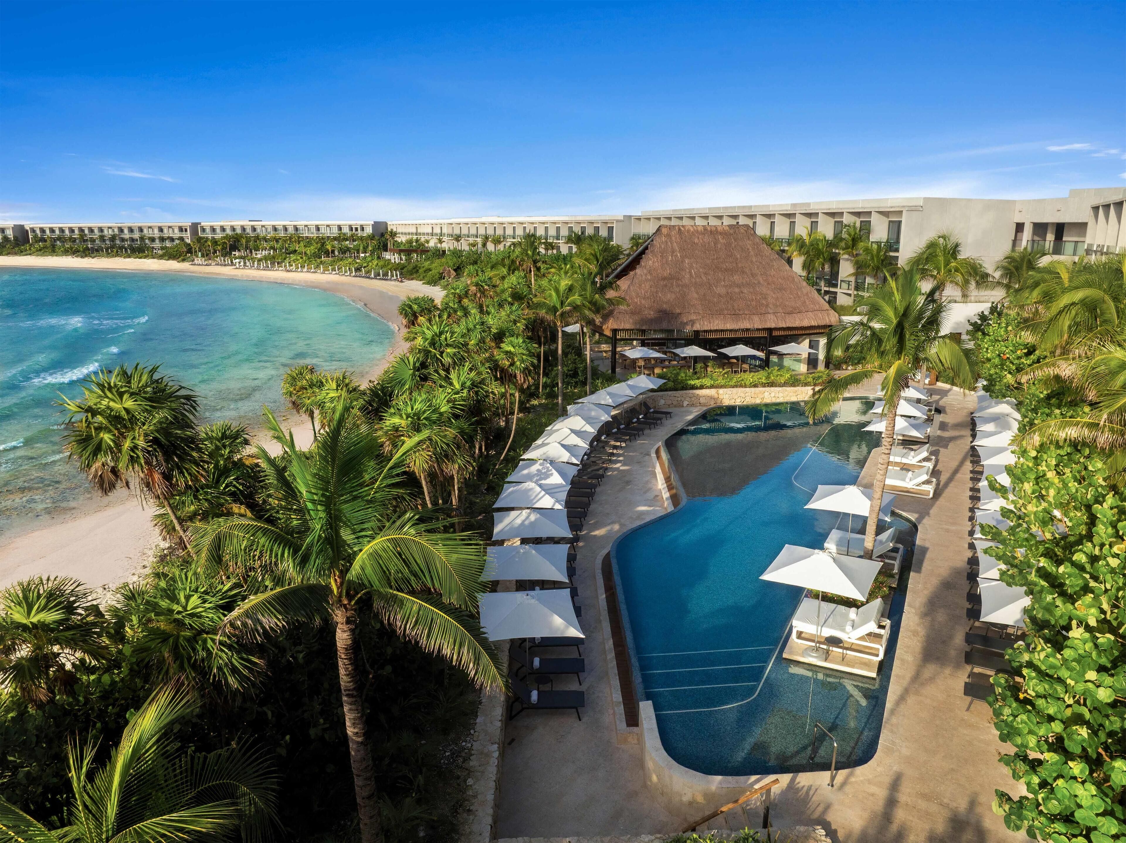 Ein Resort mit Pool, Strand und Palmen.