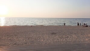 En strand med en träpromenad som leder ner till vattnet.