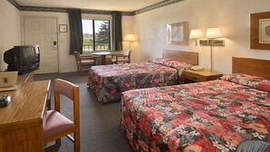 Habitación de hotel con dos camas, un escritorio, una silla, un televisor y una ventana con cortinas.