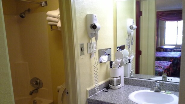 Un baño con bañera, inodoro y lavamanos. Hay dos secadores de pelo montados en la pared.
