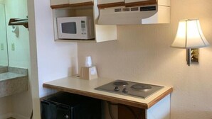 Ett kompakt kök med vita skåp, en mikrovågsugn, en diskho och en liten diskmaskin.
