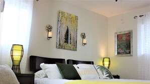 A hotel room with a bed, two bedside tables, a wall-mounted clock, and a framed picture. - Serendipity House (Colorado Springs)