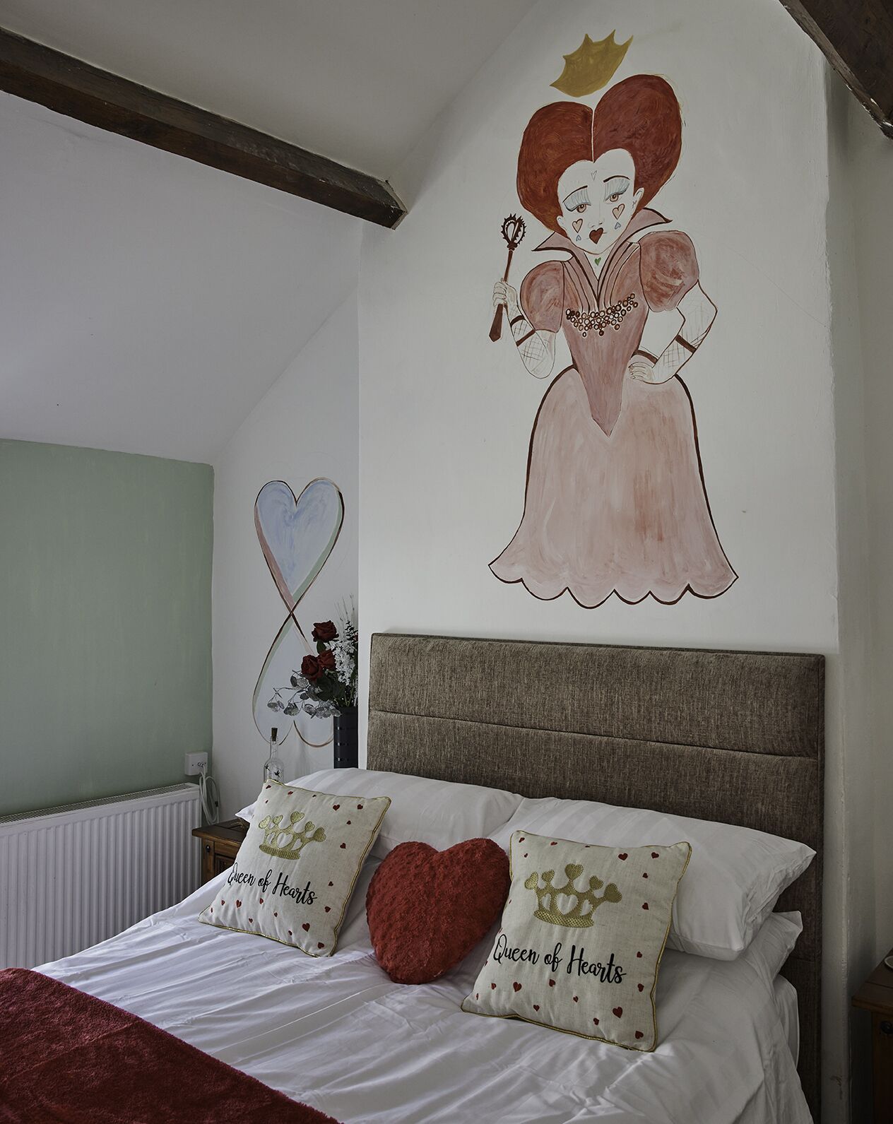 Un dormitorio con cama, almohadas, un mural en la pared y un radiador.