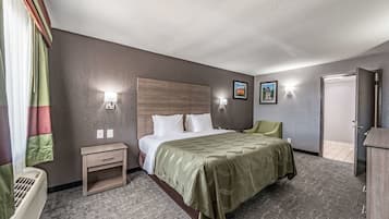Een hotelkamer met een bed, nachtkastje, lamp en uitzicht.