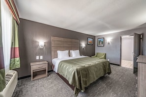 A hotel room with a bed, bedside table, lamp, and a view of the outside. - Quality Inn I-10 East Near Frost Bank Center (San Antonio)