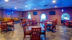 Ein Restaurant mit Backsteinwänden, Holztischen und roten Stühlen.