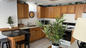 A kitchen with wooden cabinets, a sink, a stove, and a potted plant.