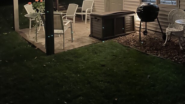 An outdoor patio area with string lights, a grill, and outdoor furniture.