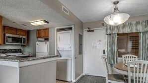 A compact kitchen with a microwave, stove, and refrigerator. There is a dining area with a table and chairs.