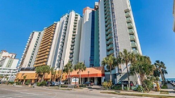 A high-rise hotel with multiple floors, balconies, and a clear blue sky.