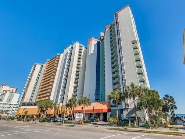A high-rise hotel with multiple floors, balconies, and a clear blue sky. - The Strand - A Boutique Resort (Myrtle Beach)