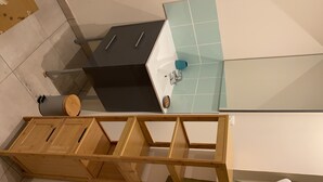 Une salle de bain avec un lavabo noir, un robinet bleu et un meuble-lavabo en bois.