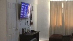 A living room with a TV, a glass-top table, and a sofa. - Casa Gueza (Benito Juarez)