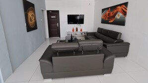 Uma sala de estar moderna com um sofá modular, uma televisão de tela plana e obras de arte nas paredes.