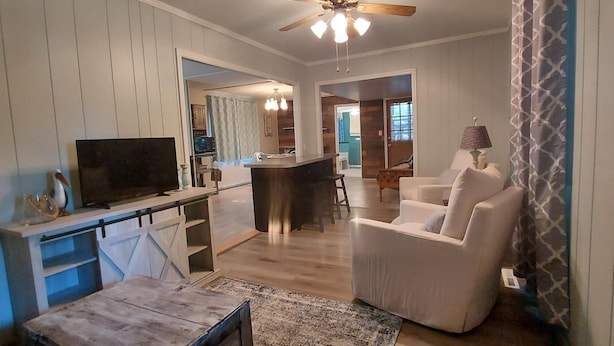 Una sala moderna con televisor, comedor y cocina al fondo.